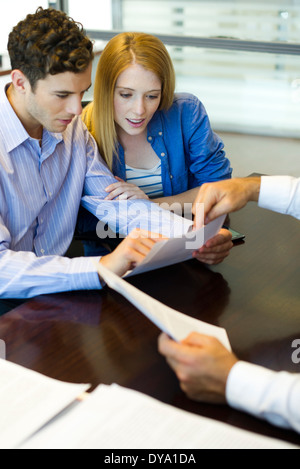Clienti in cerca di documenti cartacei in ufficio Foto Stock