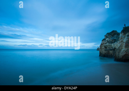 L'uomo la pesca dagli scogli a Praia da Dona Ana, Lagos al crepuscolo Foto Stock