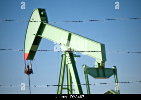 Oil Rig lavorando dietro al filo spinato sul cielo blu sullo sfondo Foto Stock