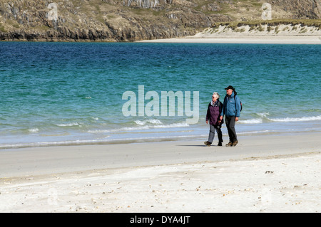 Coppia matura camminando lungo una spiaggia nelle Western Isles Foto Stock