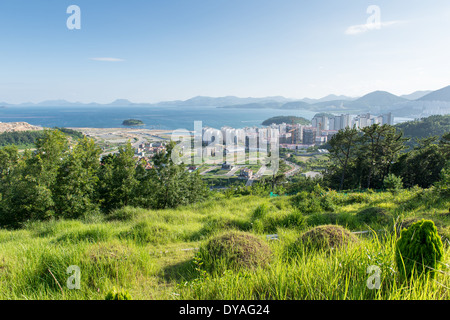 Panorama di Yeosu in Corea del sud come si vede dalle montagne circostanti con la foresta, oceano e alloggiamento sito in costruzione Foto Stock