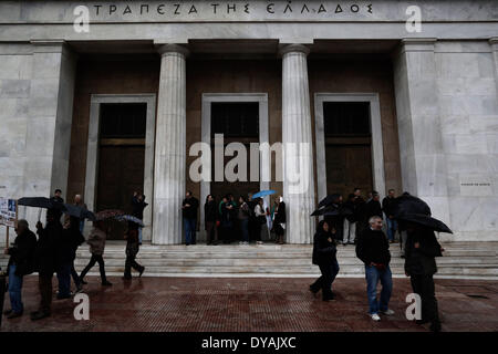 Atene, Grecia. Xi Apr, 2014. Manifestanti cercando di proteggere se stessi dalla pioggia in ingresso della Banca di Grecia filiale. Credito: Konstantinos Tsakalidis/Alamy Live News Foto Stock