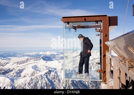 Un turista si erge nel 'Step nel vuoto' box di vetro sulla Aiguille du Midi (3842m) mountain top sopra Chamonix Monte Bianco Foto Stock