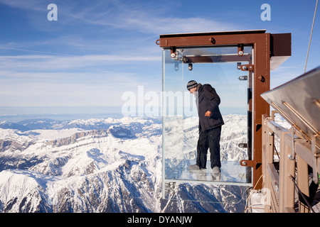Un turista si erge nel 'Step nel vuoto' box di vetro sulla Aiguille du Midi (3842m) mountain top sopra Chamonix Monte Bianco Foto Stock
