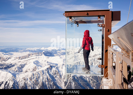 Un turista si erge nel 'Step nel vuoto' box di vetro sulla Aiguille du Midi (3842m) mountain top sopra Chamonix Monte Bianco Foto Stock
