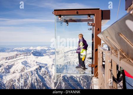 Un turista si erge nel 'Step nel vuoto' box di vetro sulla Aiguille du Midi (3842m) mountain top sopra Chamonix Monte Bianco Foto Stock
