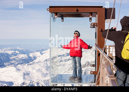 Un turista si erge nel 'Step nel vuoto' box di vetro sulla Aiguille du Midi (3842m) mountain top sopra Chamonix Monte Bianco Foto Stock