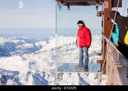 Un turista si erge nel 'Step nel vuoto' box di vetro sulla Aiguille du Midi (3842m) mountain top sopra Chamonix Monte Bianco Foto Stock