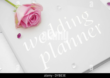 Wedding planner libro con una rosa rosa sulla parte superiore Foto Stock