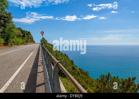 Svuotare strada asfaltata e bella vista sul Mar Mediterraneo da sopra sotto il cielo blu in Liguria, Italia. Foto Stock