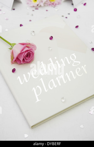 Wedding planner libro con una rosa rosa sulla parte superiore Foto Stock