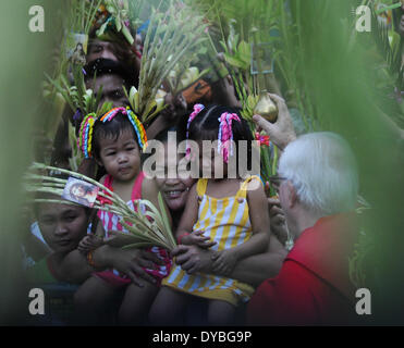 Manila, Filippine. Xiii Apr, 2014. MANILA, Filippine - Una donna e i suoi figli avere annaffiato dal sacerdote con acqua santa prima della celebrazione della Santa Messa la Domenica delle Palme presso il Santuario Nazionale di Nostra Madre del Perpetuo Soccorso a Baclaran, Paranaque city, a sud di Manila il 13 aprile 2014. La Domenica delle Palme è celebrata dai cattolici filippini che commemora la venuta di Gesù in mezzo a Gerusalemme e segna l'inizio della Settimana Santa, che viene osservato dai cattolici di tutto il mondo. Credito: George Calvelo/NurPhoto/ZUMAPRESS.com/Alamy Live News Foto Stock