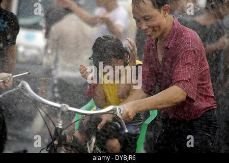 Yangon, Myanmar. Xiii Apr, 2014. Un uomo e il suo bambino partecipa alla celebrazione della festa dell'acqua in una strada a Yangon, Myanmar, 13 aprile 2014. Il Myanmar è Thingyan tradizionale festa dell'acqua ha dato dei calci a fuori di Yangon Domenica. (Xinhua/U Aung) Foto Stock