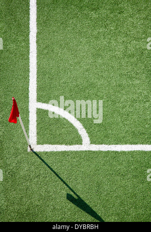 Campo di calcio. Angolo bianco linea contro terra verde e rosso bandiera a colori Foto Stock