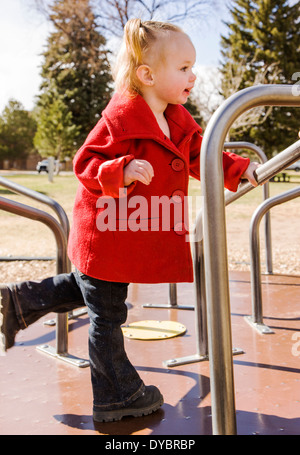 Carino, adorabile 16 mese bambina gioca su un parco giochi per bambini, merry-go-round Foto Stock