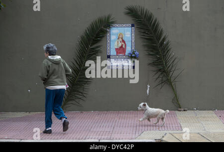 Buenos Aires, Argentina. Xiii Apr, 2014. Una donna e il suo cane a camminare di fronte a un'immagine decorata con mazzi durante la celebrazione della Domenica delle Palme a Buenos Aires, capitale dell'Argentina, il 13 aprile 2014. La Domenica delle Palme segna l inizio della Settimana Santa la Chiesa Cattolica Romana calendario. Credito: Martin Zabala/Xinhua/Alamy Live News Foto Stock