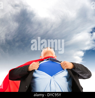 Imprenditore imitare superman per tirare la sua t-shirt aperto con dark cloud Foto Stock