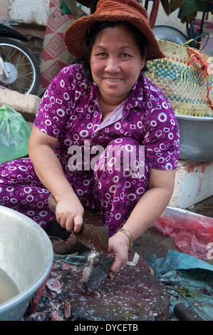 Donna sminuzzare il pesce nel mercato a Kratie, Cambogia Foto Stock