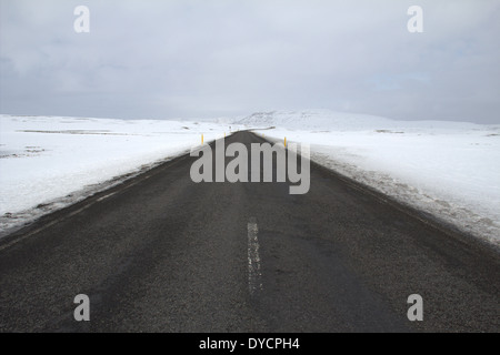 Vuoto lungo strada innevata in Islanda la voce off all'orizzonte Foto Stock