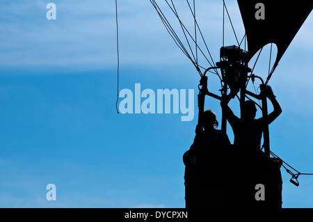 Una mongolfiera con due persone rising profilarsi davanti un nebuloso cielo blu Foto Stock