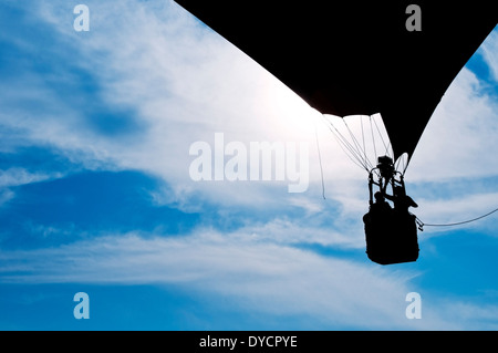 Una mongolfiera con due persone rising profilarsi davanti un nebuloso cielo blu Foto Stock