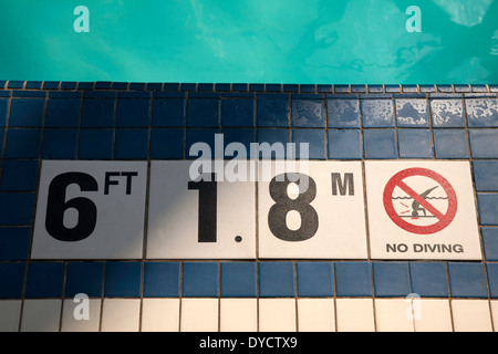 Piscina piastrelle dare profondità in piedi e metri, più un avviso di non immersione. Foto Stock