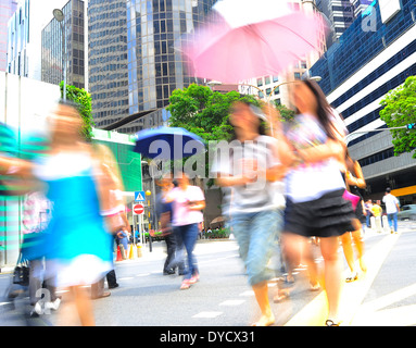 Le donne non identificato con ombrelloni attraversando la strada di Singapore Foto Stock