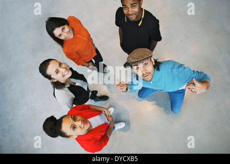 Vista aerea di giovani in piedi insieme alla ricerca fino alla fotocamera elegante con il giovane uomo gesticolando. Team o Gruppo. Foto Stock