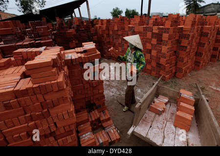 Una donna pile mattoni in una fabbrica in ben tre, Delta del Mekong, Vietnam. Foto Stock