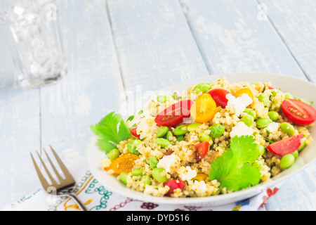 Tabulé fatta con bulgar, edamame, rosso e giallo di pomodori ciliegini, i cipollotti, il coriandolo, il formaggio feta sbriciolato, pesto di limone Foto Stock