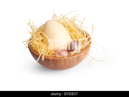 Una ciotola di legno di uova di pasqua di cioccolato avvolto in colorati lamina di stagno su uno sfondo bianco. Foto Stock