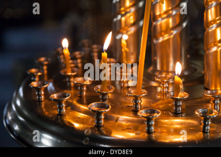 Piccole candele accese in un buio Chiesa Ortodossa Foto Stock