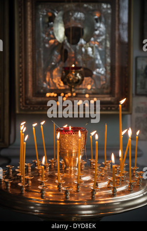 Le candele accese in un buio Chiesa Ortodossa sopra antica icona Foto Stock