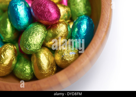 Colouful stagnola avvolto le uova di pasqua in una ciotola su un isolato bianco sullo sfondo. Foto Stock