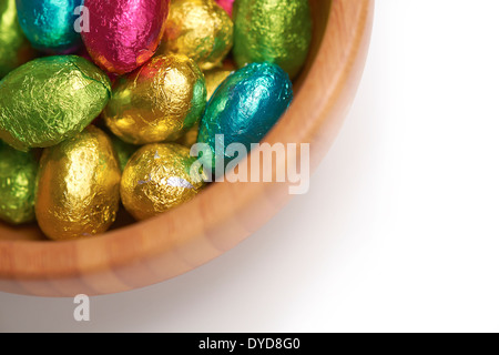 Colouful stagnola avvolto le uova di pasqua in una ciotola su un isolato bianco sullo sfondo. Foto Stock