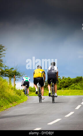 I ciclisti su una ripida collina con una tempesta di avvicinamento. Foto Stock