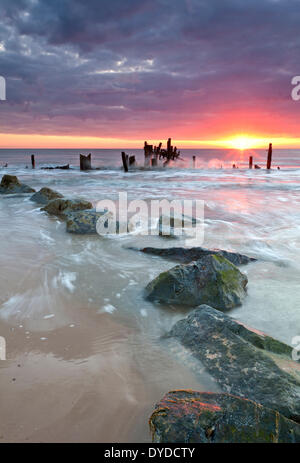 Happisburgh la spiaggia e il mare abbandonati difese a sunrise sulla costa di Norfolk. Foto Stock