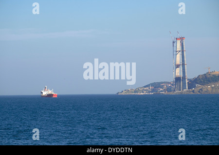 Contenitore nave passando il nuovo terzo ponte che è in costruzione sul Bosforo, Istanbul, Turchia. Foto Stock