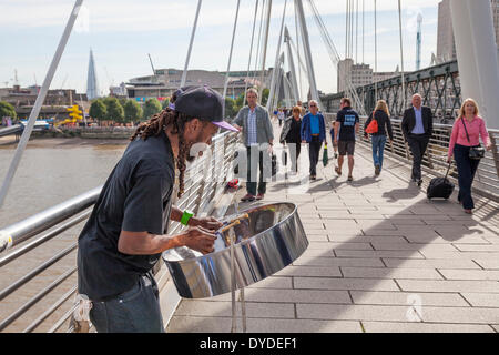 Busker riproduzione di nastro di acciaio tamburo sul Giubileo d oro ponte pedonale sul Tamigi da Hungerford Bridge. Foto Stock