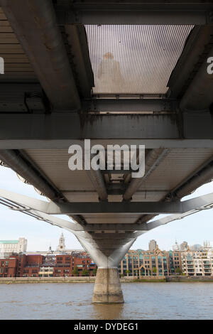 Il lato inferiore del Millennium Bridge con il fiume Tamigi e un pedone vede attraverso la maglia. Foto Stock