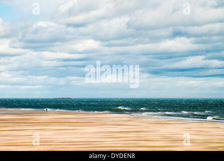 Giornata di vento sulla spiaggia sabbiosa tra Bamburgh Seahouses e. Foto Stock