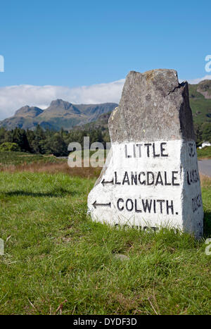 Stone Road Sign vicino a Elterwater con Langdale Pikes in background. Foto Stock