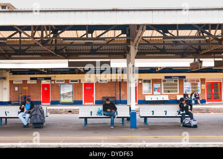 I passeggeri sulla piattaforma panche in attesa alla stazione di Woking. Foto Stock