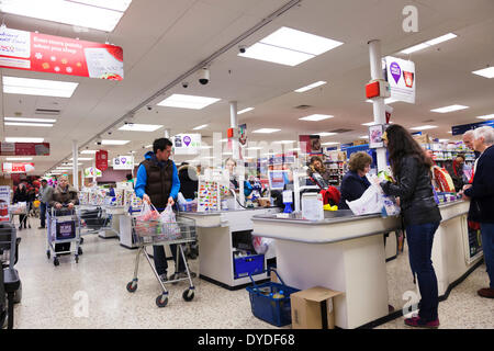 I clienti andando attraverso staffed casse al supermercato Tesco. Foto Stock