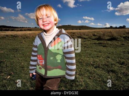 Un allegro bimbo di 2 anni in piedi in un campo. Foto Stock