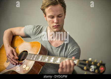 Un bel giovane uomo suonare la chitarra acustica. Foto Stock