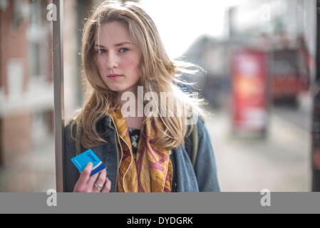 Una giovane donna trattiene un Oyster card a Londra la fermata degli autobus. Foto Stock