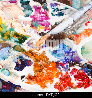 Utilizzate la palette artistiche con corse di vernici a olio e due pennelli Foto Stock