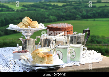 Un pomeriggio Devonshire tè alla crema con clotted cream, marmellata e un cioccolato pan di spagna con campi rurali in background REGNO UNITO Foto Stock