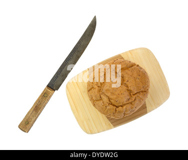 Un piccolo insieme di frumento boule il pane su un legno tagliere con un vecchio coltello da cucina a lato. Foto Stock